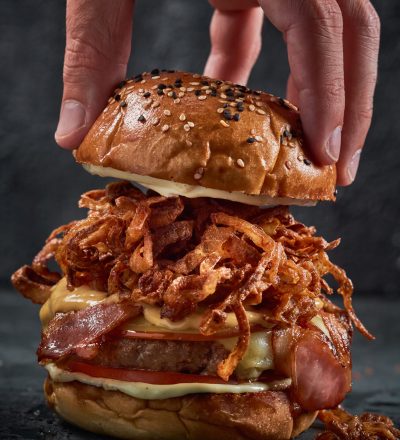 vertical-shot-male-s-hand-grabbing-burger-s-upper-bun